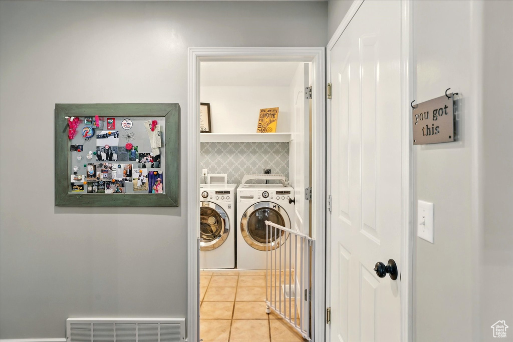 Laundry area with washing machine and clothes dryer and light tile patterned floors
