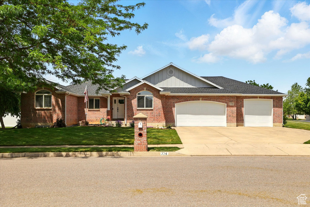 Ranch-style house featuring driveway, a garage, a front yard, brick siding, and roof with shingles