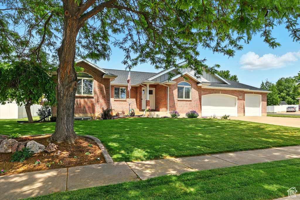 Ranch-style house featuring concrete driveway, an attached garage, a front lawn, and brick siding