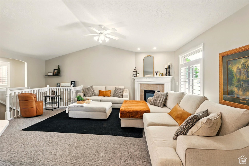 Carpeted living area with a ceiling fan and a tile fireplace
