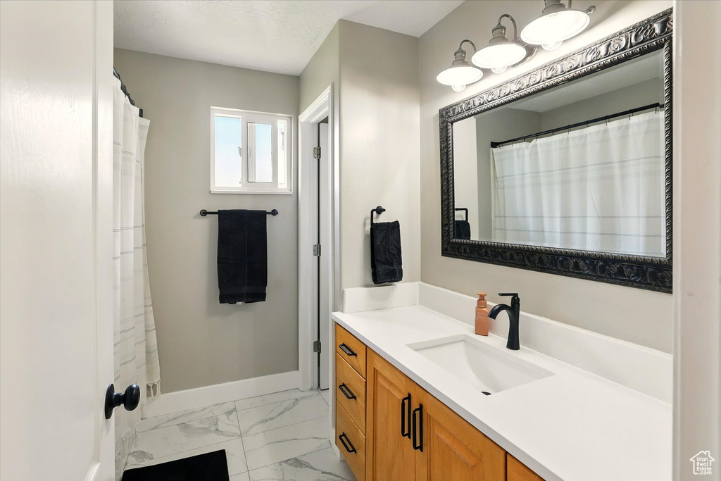 Bathroom featuring marble look tile flooring, vanity, and baseboards