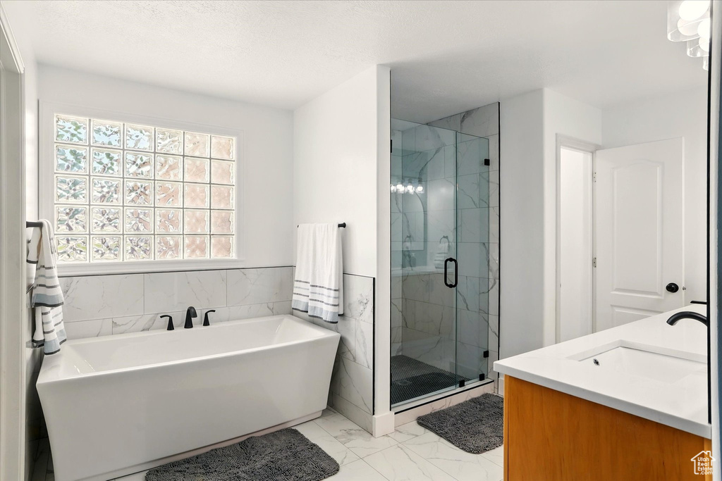 Full bathroom with marble finish flooring, a freestanding tub, a marble finish shower, and vanity