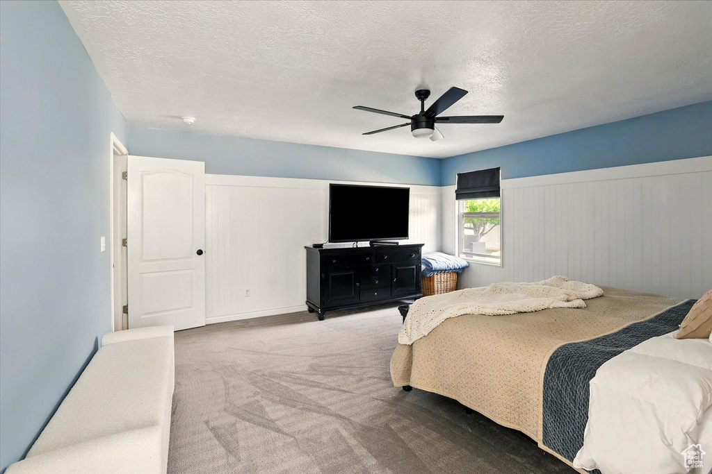 Carpeted bedroom with a textured ceiling and a ceiling fan
