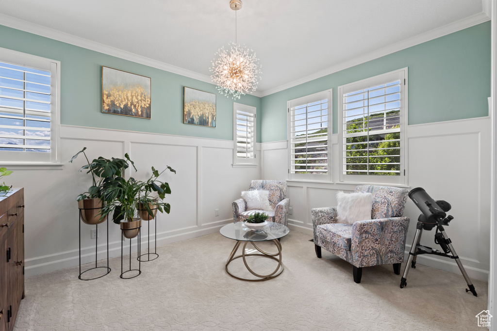 Living area with a wainscoted wall, carpet, crown molding, a decorative wall, and a chandelier