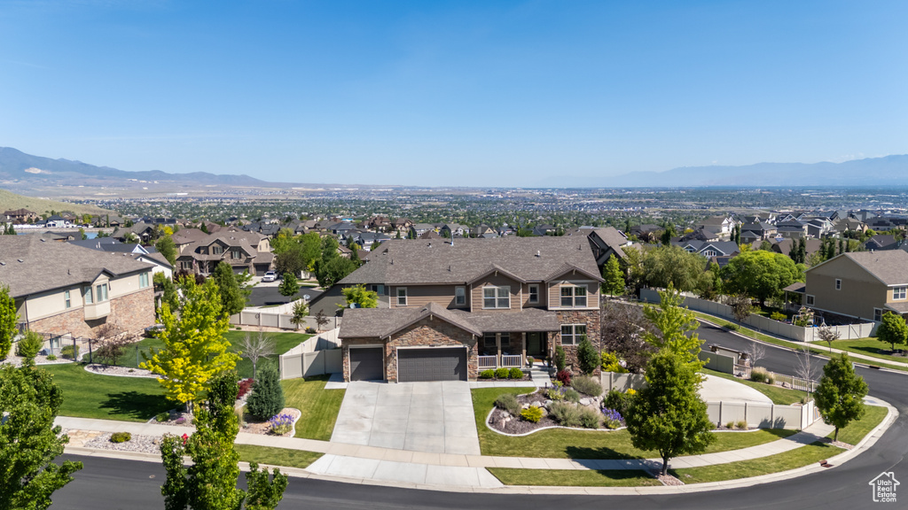 View of front of house with driveway, a residential view, stone siding, and a mountain view