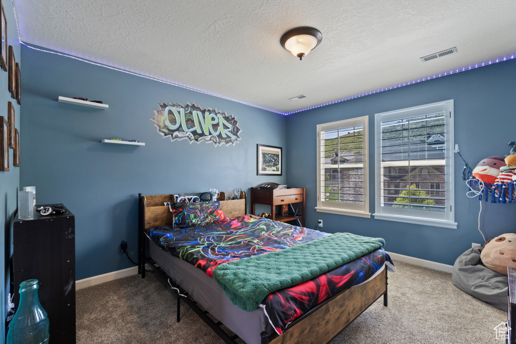 Carpeted bedroom featuring a textured ceiling and baseboards