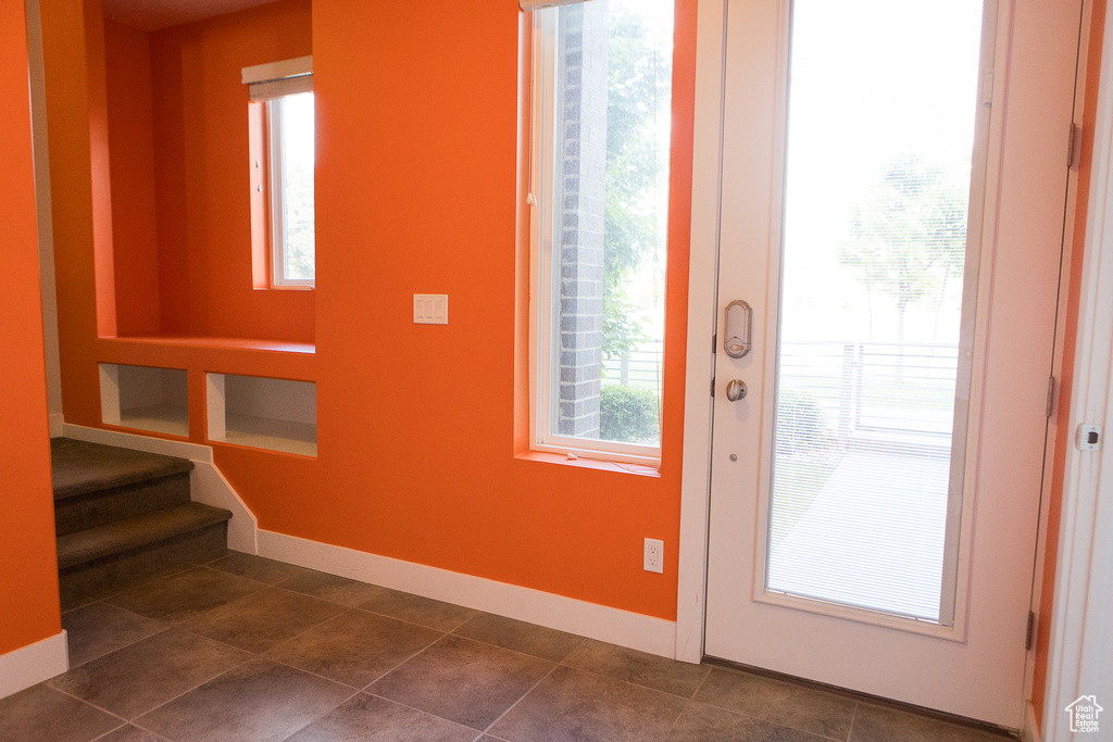 Entryway with healthy amount of natural light, stairway, and baseboards