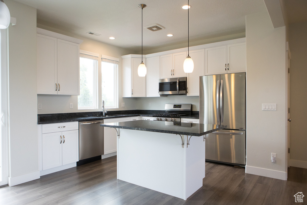 Kitchen with appliances with stainless steel finishes, dark countertops, white cabinetry, recessed lighting, and dark wood-style flooring