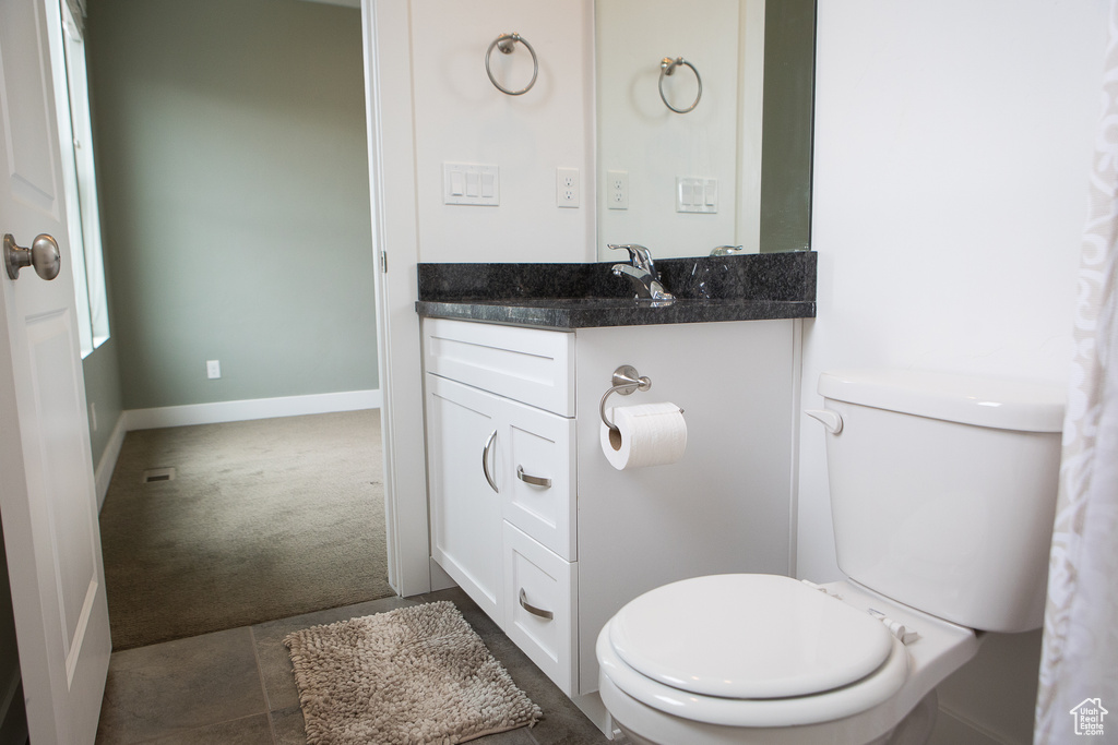 Bathroom with toilet, vanity, and baseboards