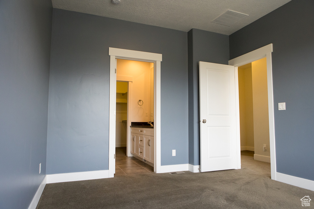 Unfurnished bedroom with carpet, baseboards, and a sink