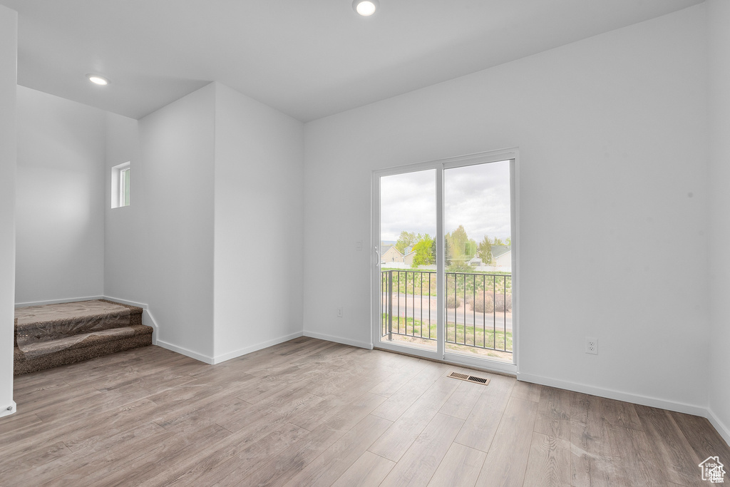 Empty room featuring plenty of natural light, wood finished floors, baseboards, stairs, and recessed lighting