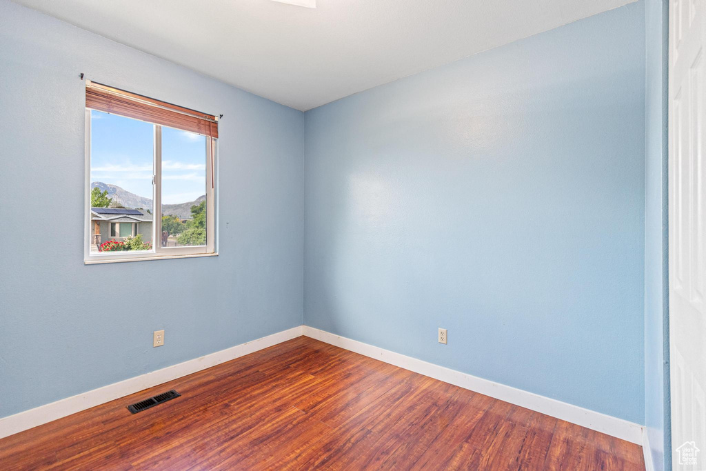 Spare room featuring baseboards and dark wood-type flooring