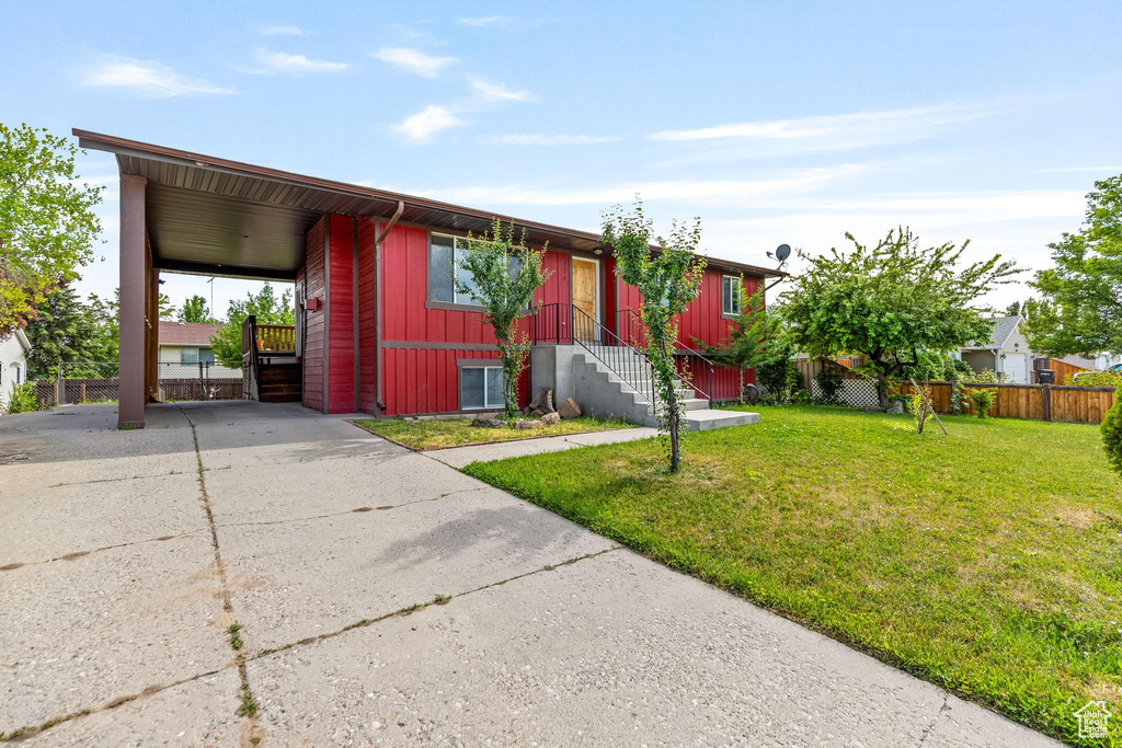 View of front of home with concrete driveway, an attached carport, and entry steps