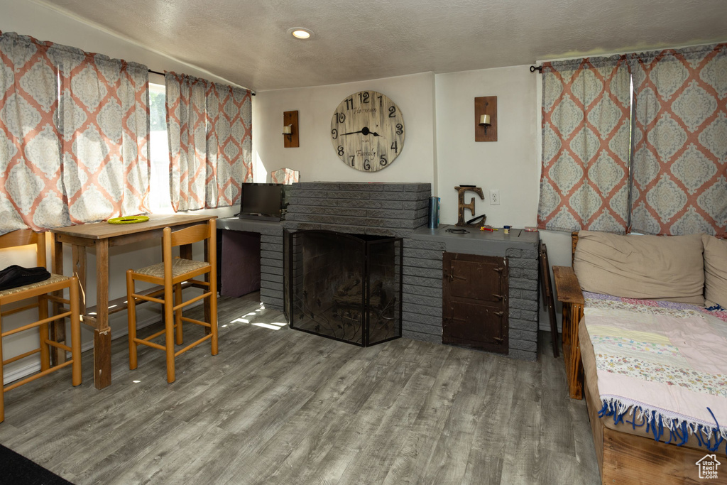 Bedroom with wood finished floors, a brick fireplace, and a textured ceiling