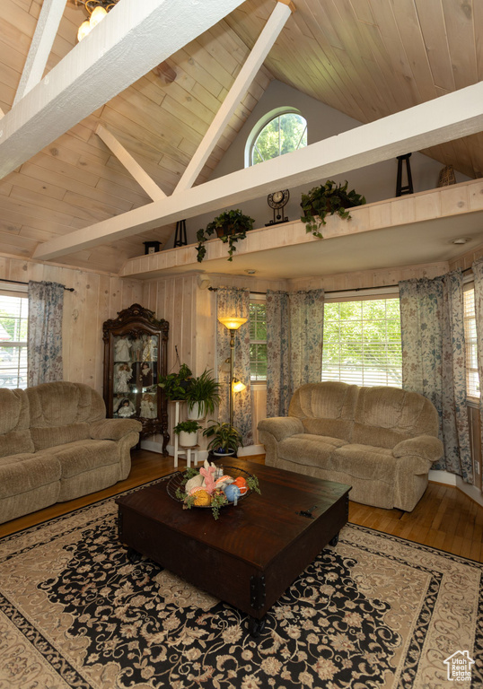 Living room featuring wooden ceiling with exposed beams, wood-type flooring, plenty of natural light, high vaulted ceiling, and wood walls