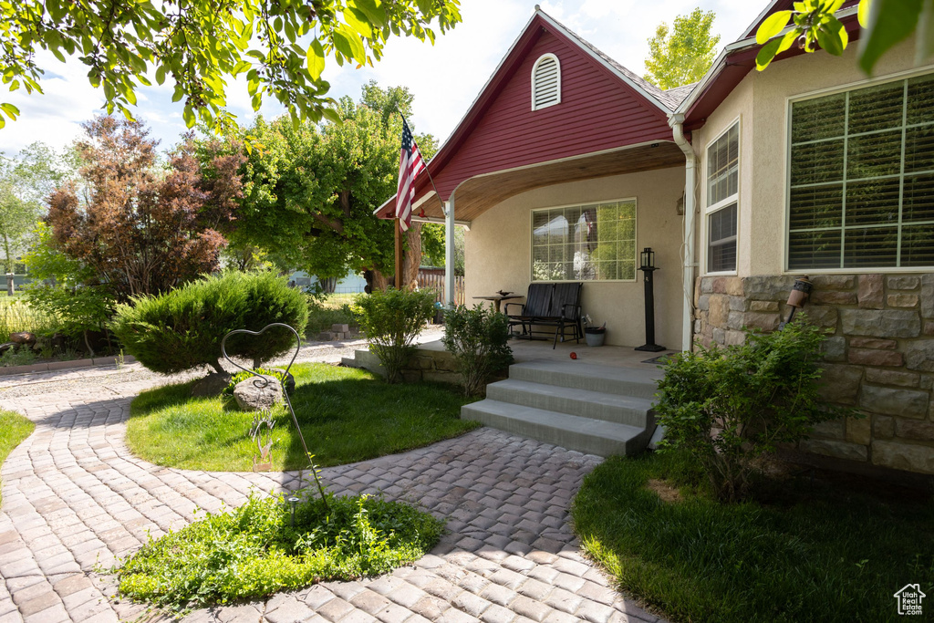 Doorway to property with stone siding, stucco siding, and covered porch