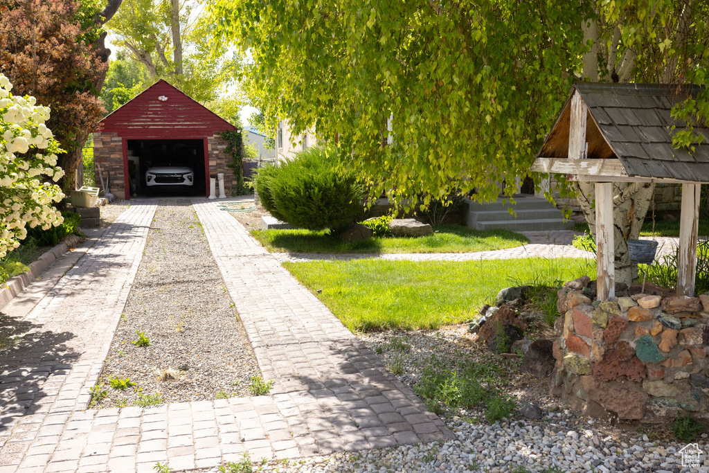 View of yard with a detached garage, an outbuilding, and driveway