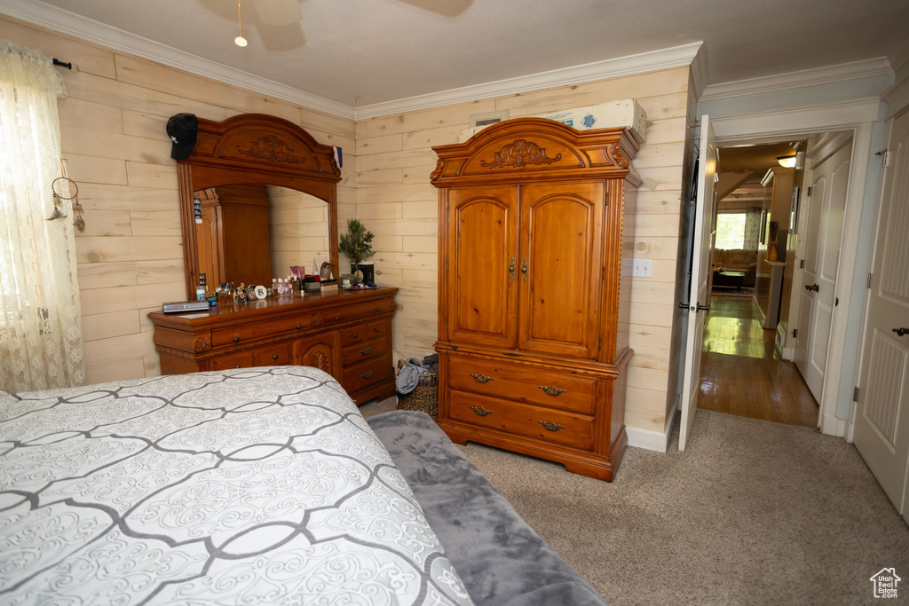 Bedroom with wood walls, crown molding, carpet, and ceiling fan