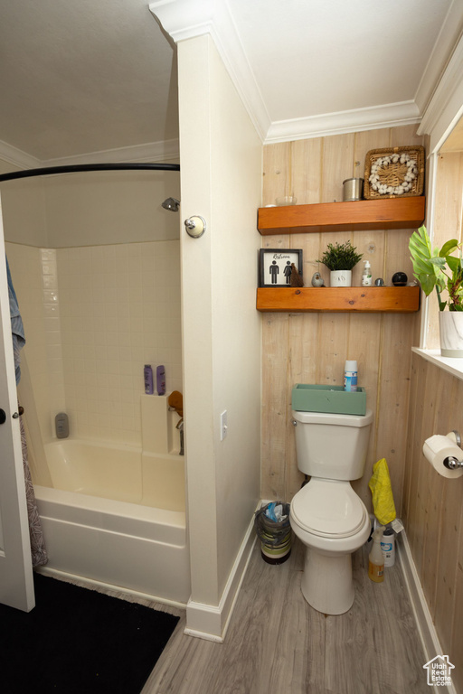 Bathroom with baseboards, wood finished floors, shower / bath combination with curtain, toilet, and crown molding