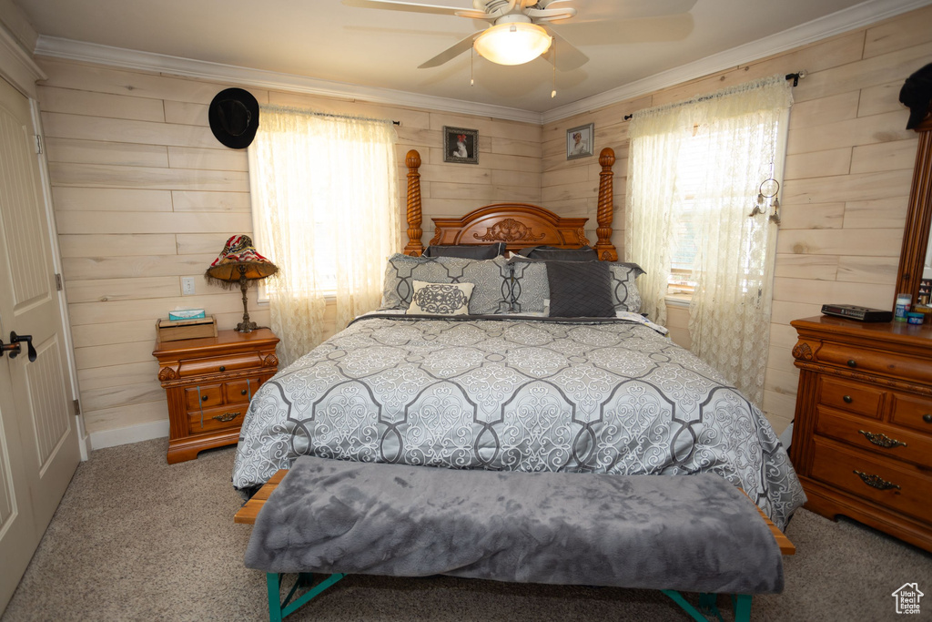 Bedroom with wooden walls, carpet, ornamental molding, baseboards, and a ceiling fan