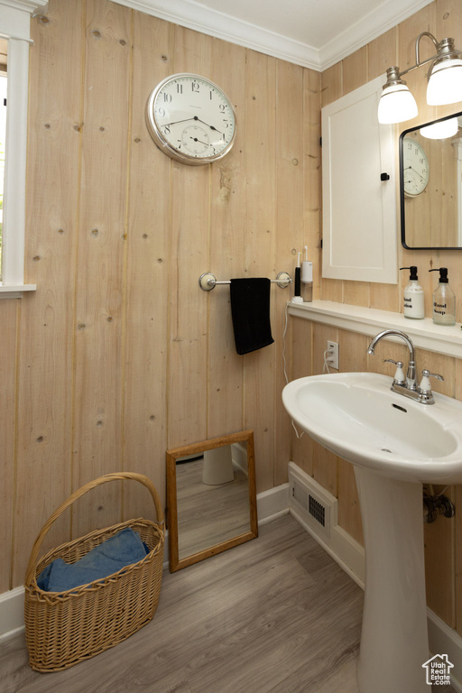 Bathroom with wood finished floors, baseboards, wooden walls, and ornamental molding