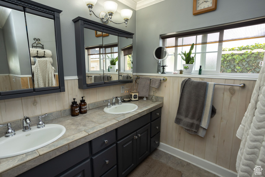 Full bath with double vanity, crown molding, wood walls, and a wainscoted wall