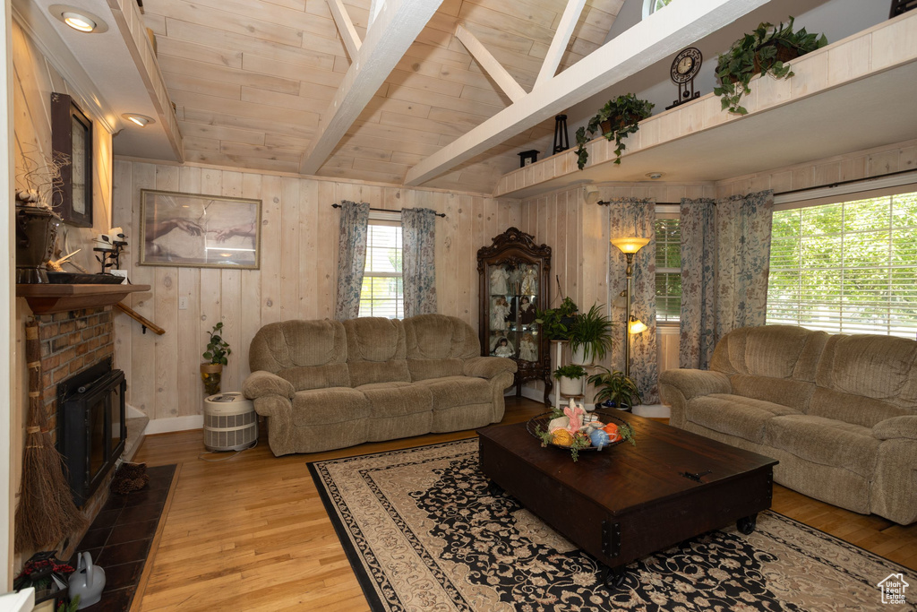 Living room featuring light wood-style floors, wood walls, wood ceiling, and a fireplace