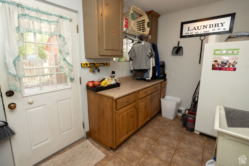 Kitchen with freestanding refrigerator, light countertops, and tile patterned flooring