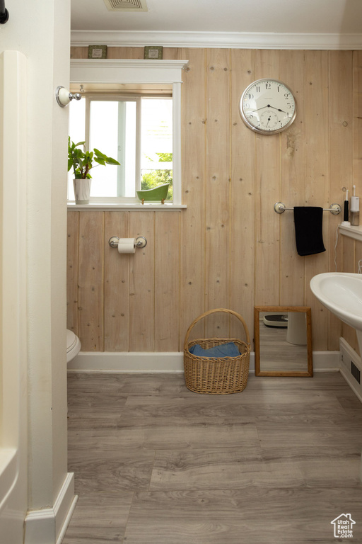 Bathroom featuring wood walls, wood finished floors, toilet, and baseboards
