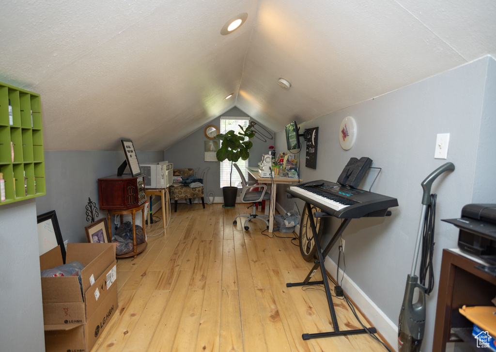 Home office with hardwood / wood-style flooring, vaulted ceiling, and baseboards