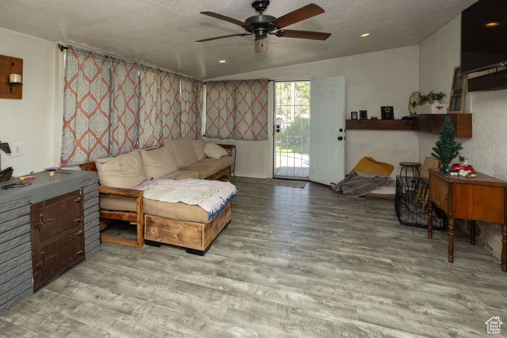 Living room with a ceiling fan, wood finished floors, a textured ceiling, and recessed lighting