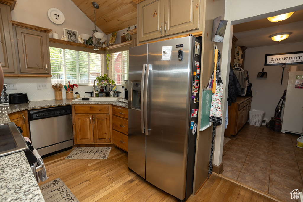 Kitchen featuring stainless steel appliances, a sink, lofted ceiling, light wood-type flooring, and decorative backsplash