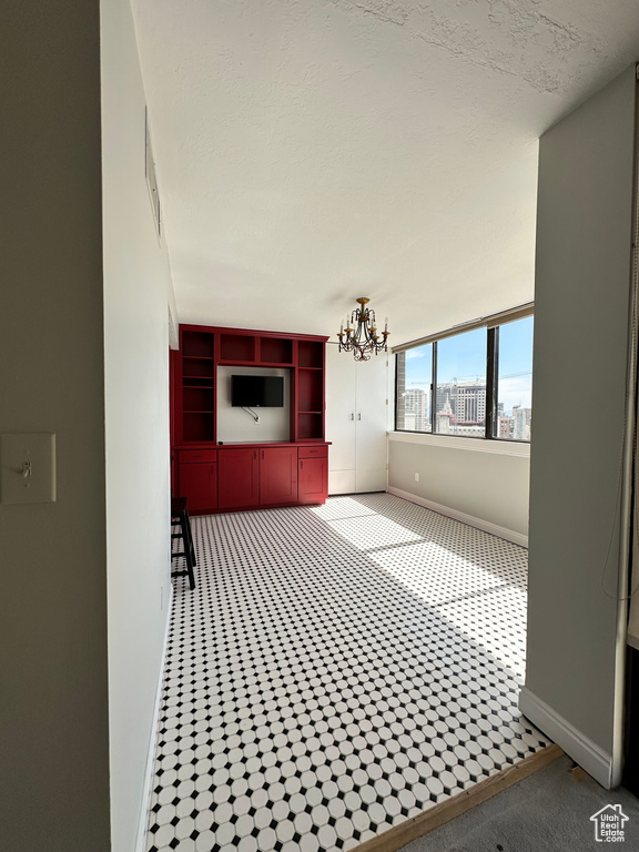 Unfurnished living room with a chandelier and baseboards