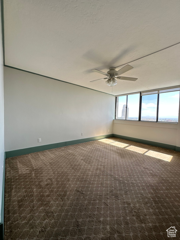 Carpeted spare room featuring ceiling fan and baseboards