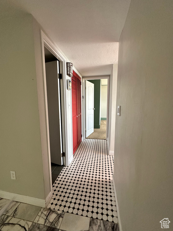 Hall with baseboards and a textured ceiling