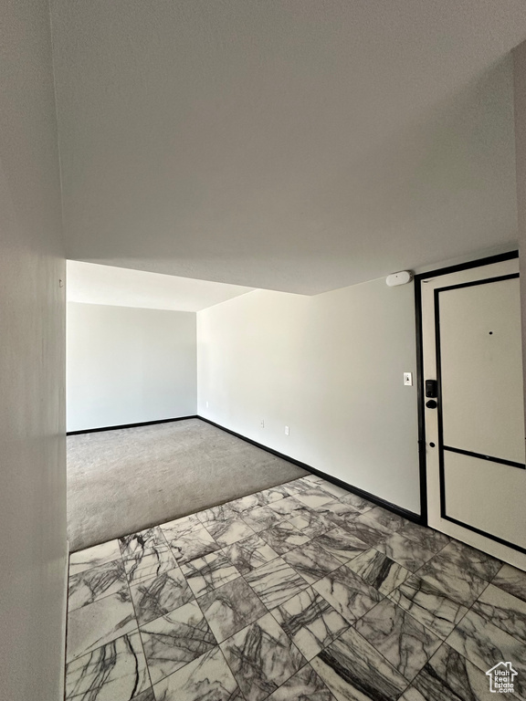 Carpeted empty room with marble finish flooring and baseboards