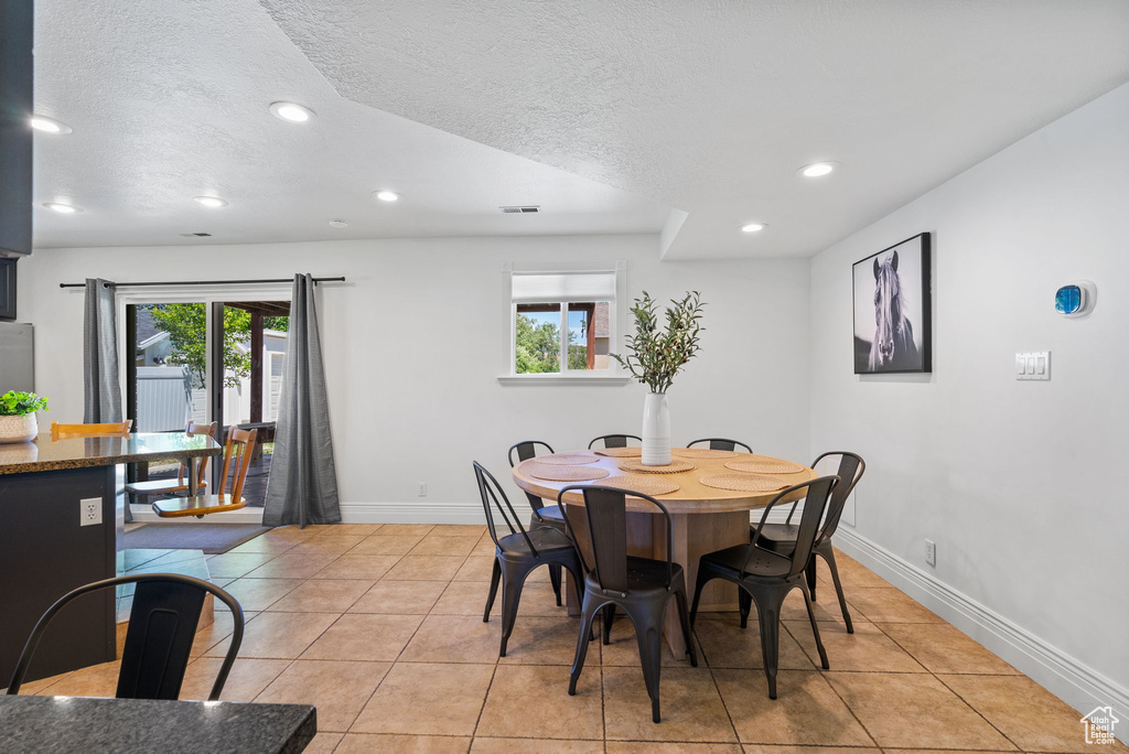 Dining space with recessed lighting, a textured ceiling, baseboards, and light tile patterned floors