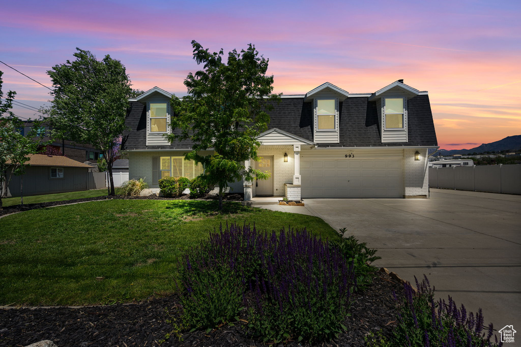 Colonial inspired home with roof with shingles, driveway, and brick siding