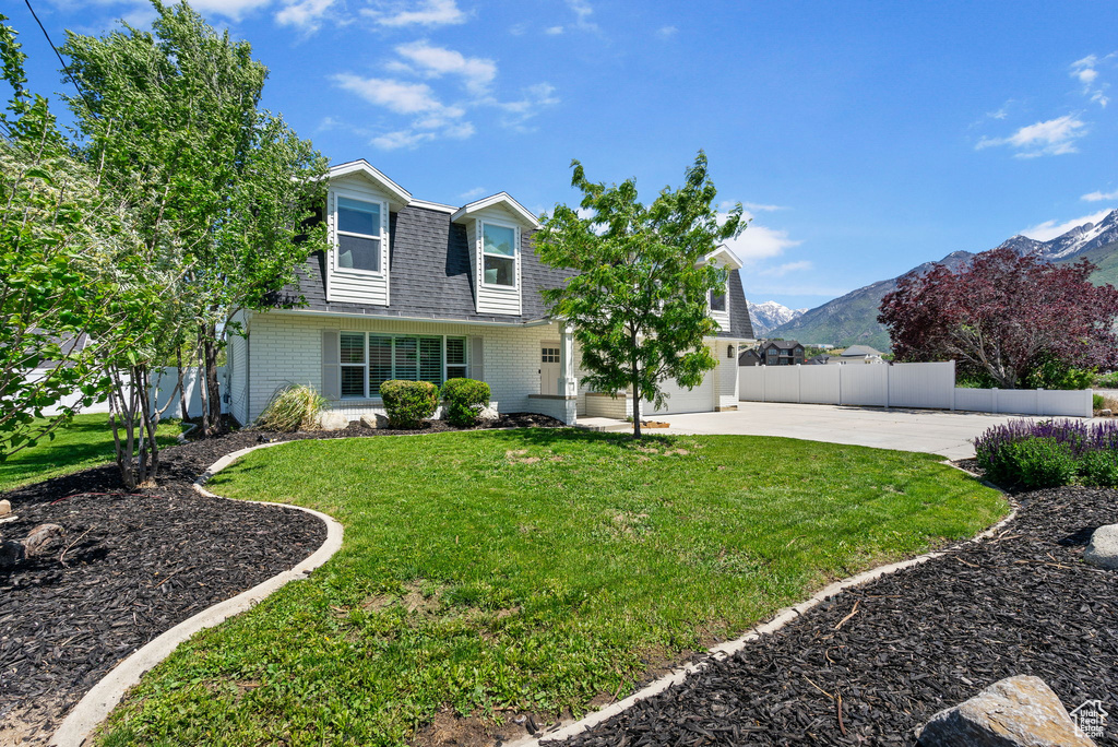View of front of property with roof with shingles, driveway, a mountain view, and brick siding