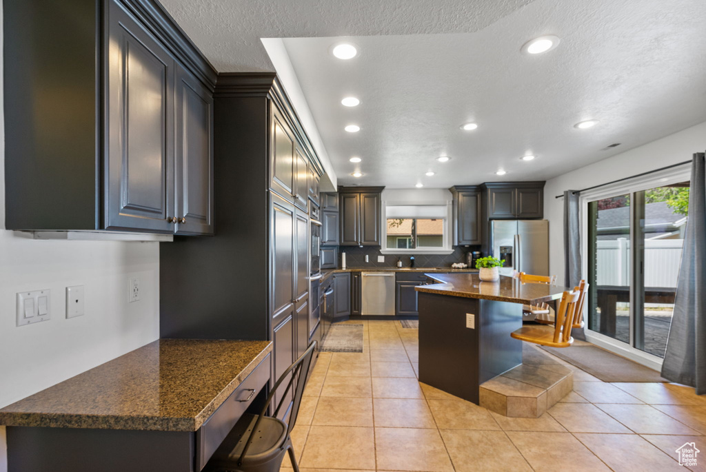 Kitchen with stainless steel dishwasher, recessed lighting, a breakfast bar area, plenty of natural light, and light tile patterned floors