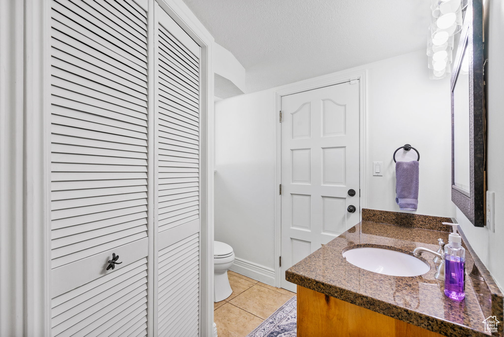 Bathroom with a closet, toilet, vanity, and tile patterned flooring