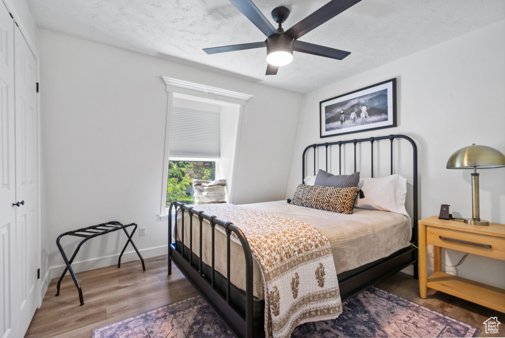 Bedroom featuring a closet, wood finished floors, baseboards, and a ceiling fan