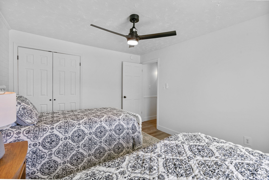 Bedroom featuring wood finished floors, a closet, ceiling fan, and baseboards