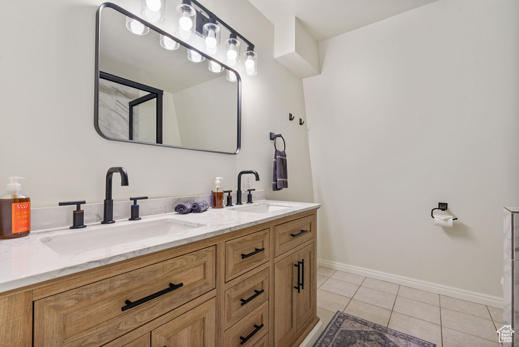 Full bath with double vanity, tile patterned flooring, and baseboards