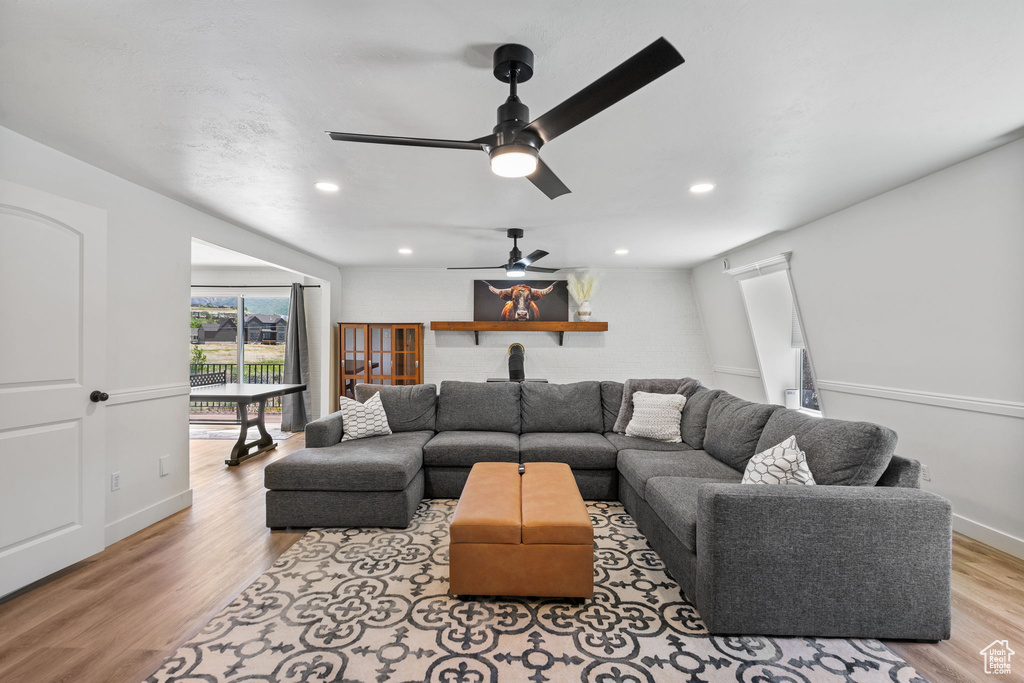 Living room featuring light wood-type flooring, ceiling fan, recessed lighting, and baseboards