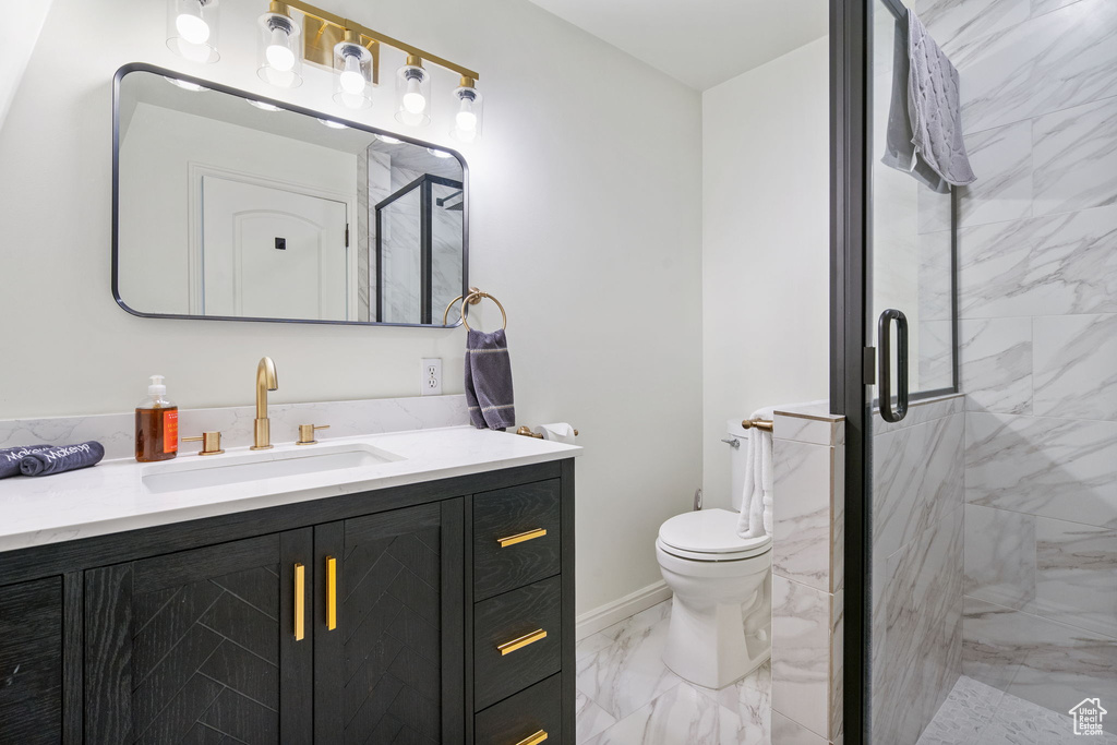 Bathroom featuring marble finish flooring, vanity, a marble finish shower, and toilet