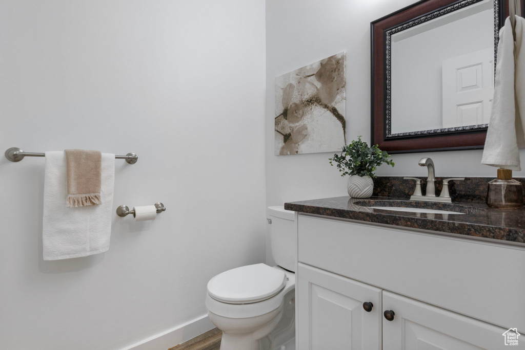 Bathroom with vanity, toilet, baseboards, and wood finished floors
