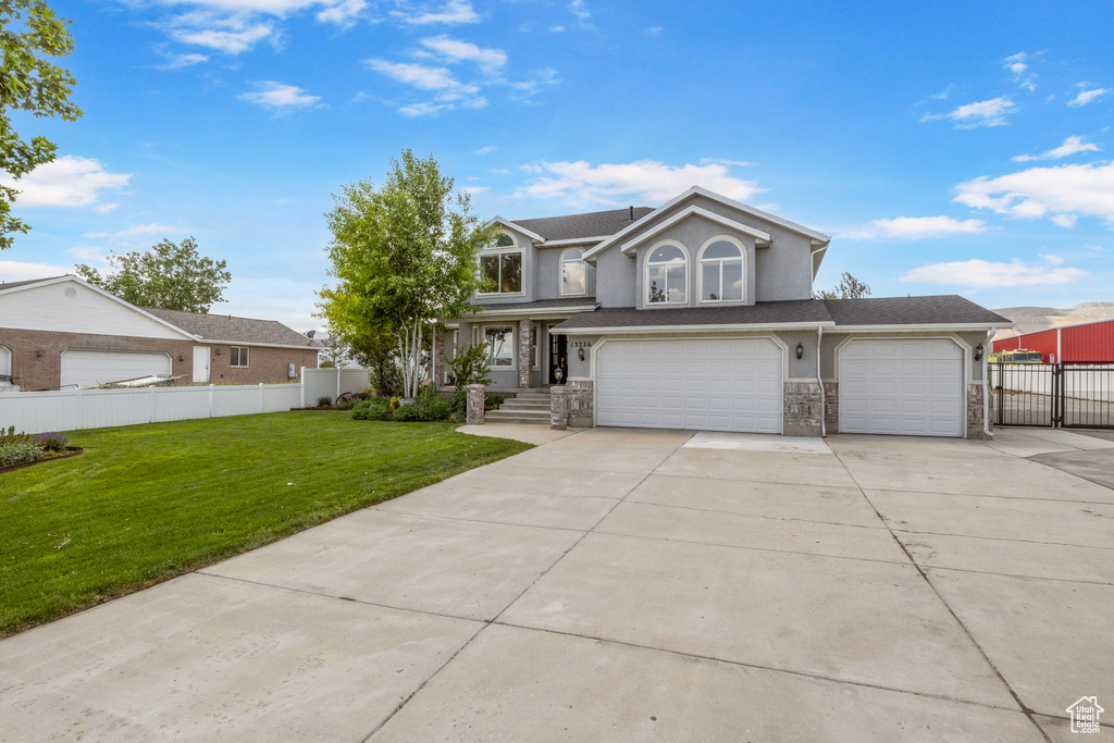 Traditional home featuring concrete driveway, stone siding, a garage, stucco siding, and an attached garage