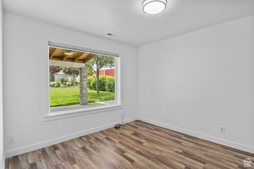 Spare room with wood finished floors, baseboards, and a textured ceiling