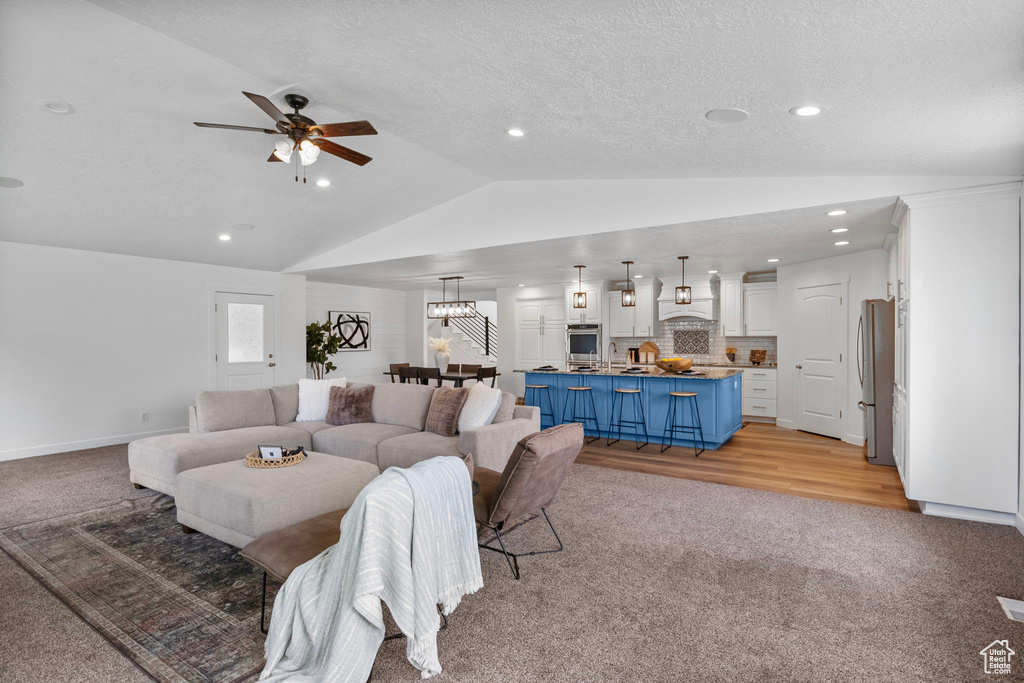 Living area with light carpet, lofted ceiling, a ceiling fan, recessed lighting, and a textured ceiling